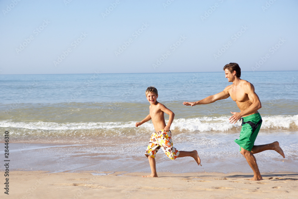 Father chasing young boy on beach