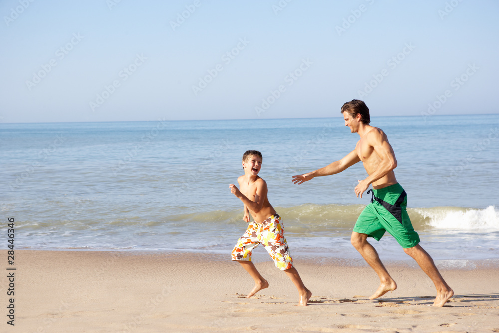 Father chasing young boy on beach