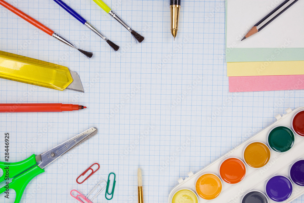 pens, pencils, paint brush and scissors on graph grid paper pens, pencils, paint brush and scissors on graph grid paper