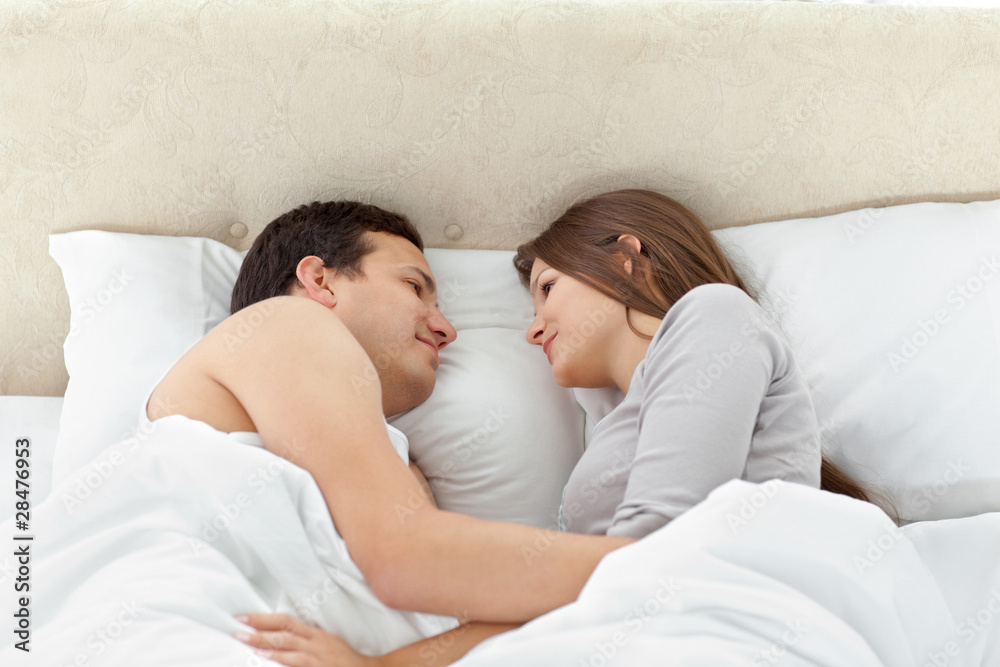 Tranquil couple looking at each other on their bed