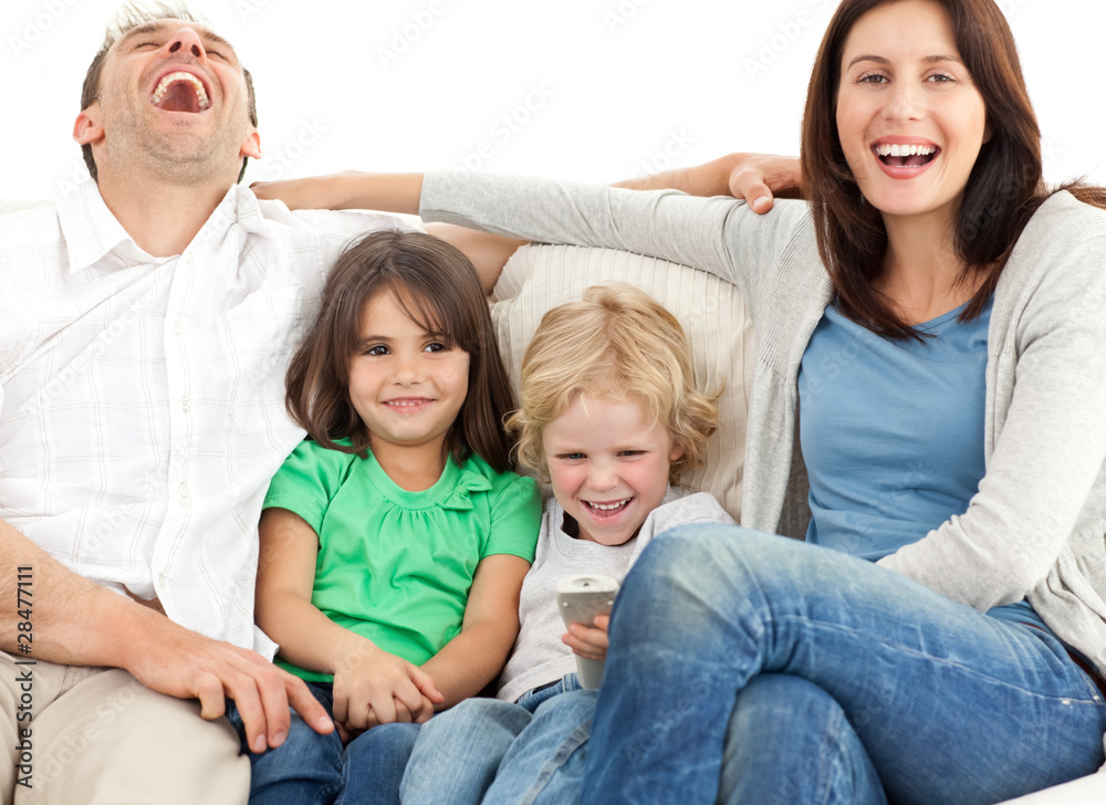 Family laughing while watching television together Family laughing while watching television together