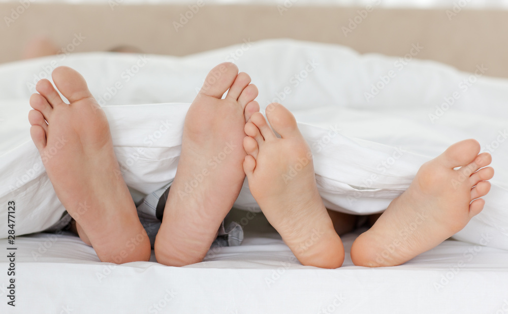 Close up of couple's feet while relaxing in their bed