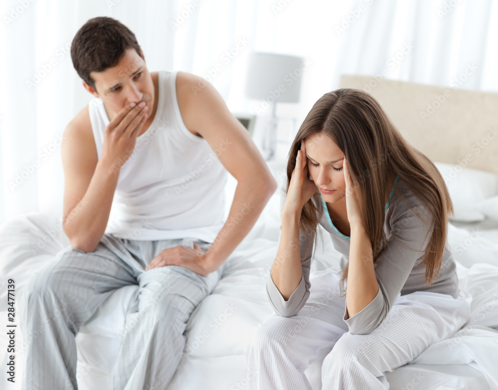 Worried man looking at his girlfriend having a headache on the b Worried man looking at his girlfriend having a headache on the b