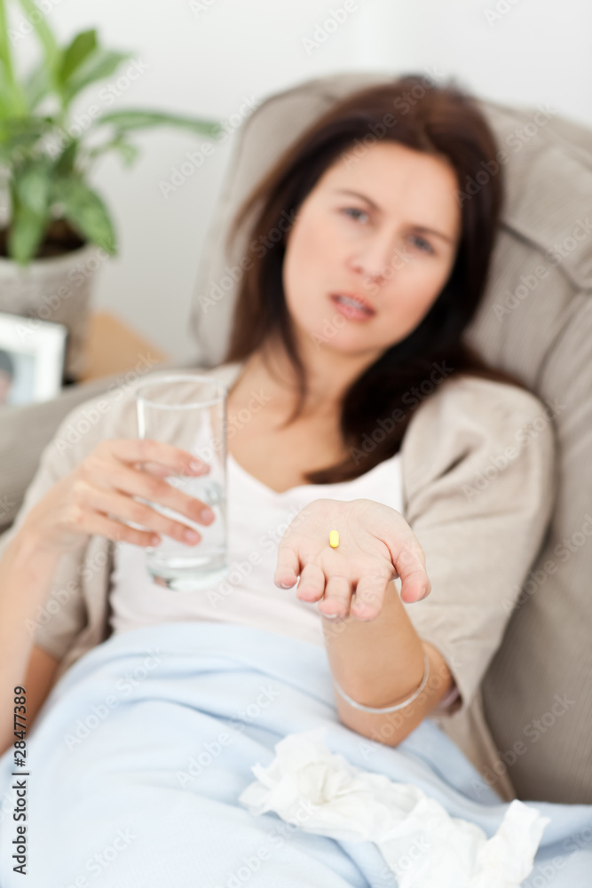 Sick woman taking her medicine on the sofa Sick woman taking her medicine on the sofa