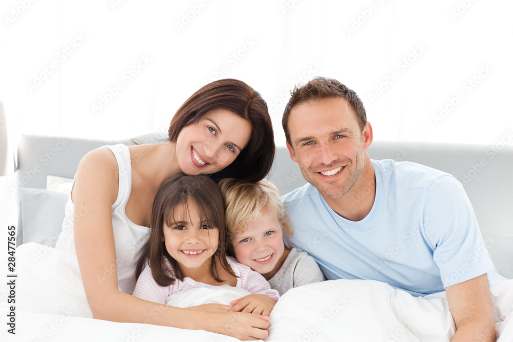 Portrait of a happy family sitting on the bed