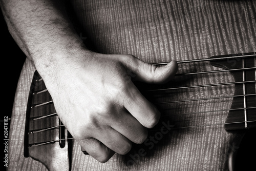 playing six-string electric bass guitar; slap technique photo