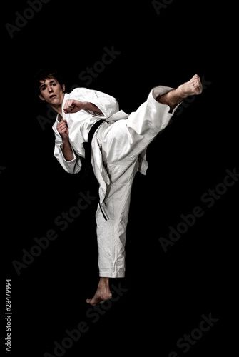 Karate male fighter young high contrast on black background.