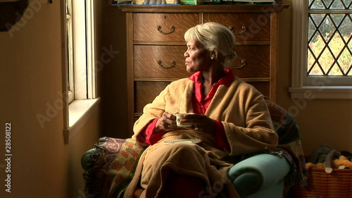 Senior woman drinking tea by bedroom window