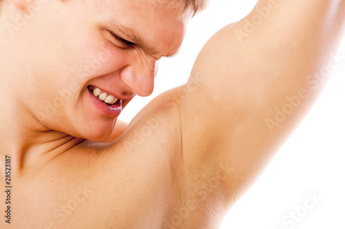 closeup of young man sniffing his armpit isolated on white