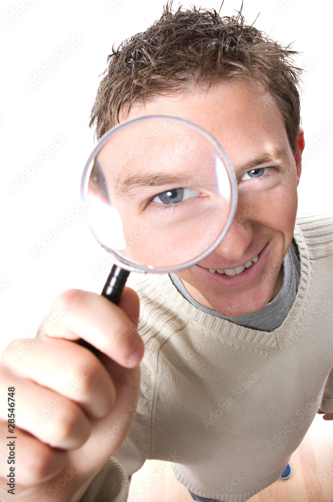 young smiling man looking through magnifying glass young smiling man looking through magnifying glass