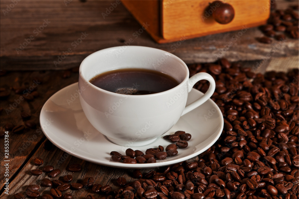 Cup of rich coffee sits on a mound of beans.