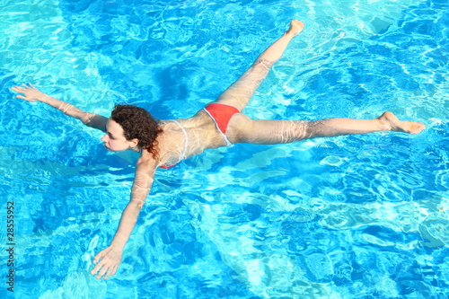 woman wearing swimming suit is swimming in swimming pool