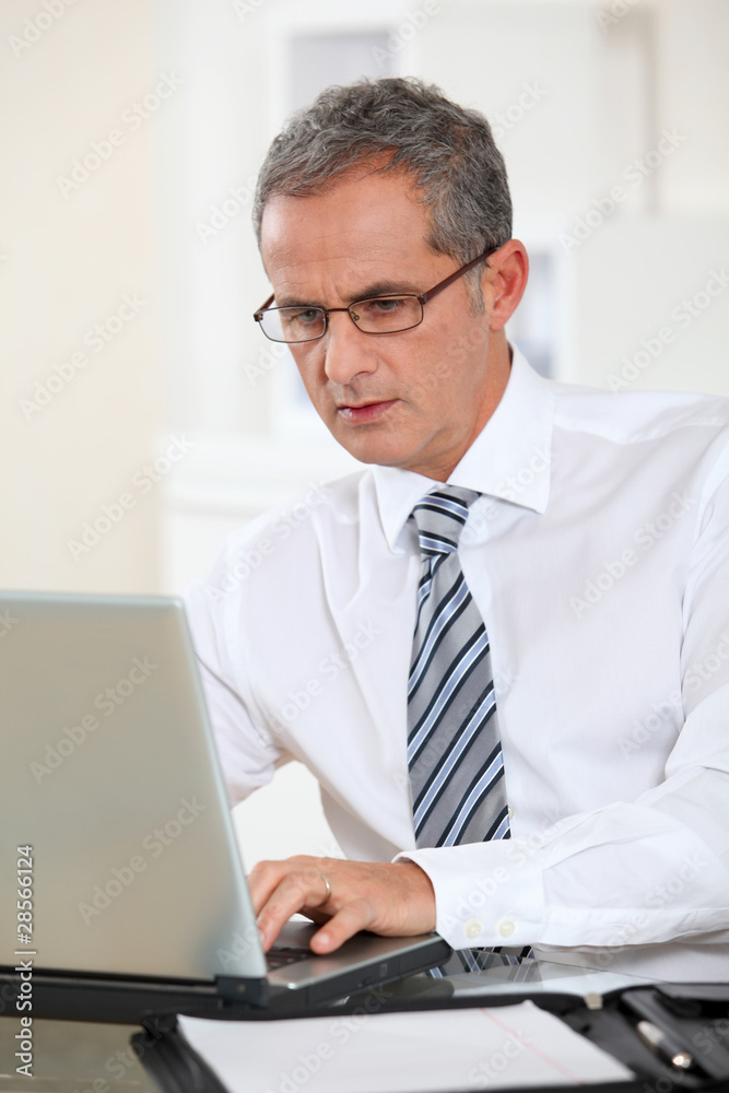 Portrait of businessman working on laptop computer Portrait of businessman working on laptop computer