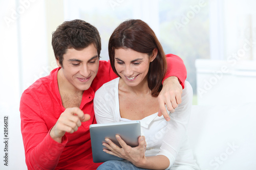 Young couple using electronic tab on sofa