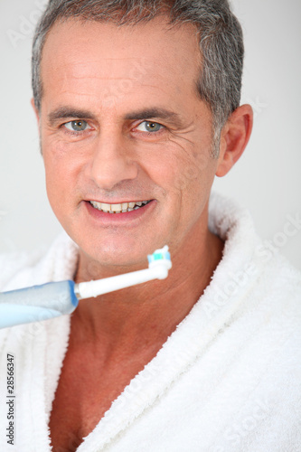Portrait of mature man using electric toothbrush