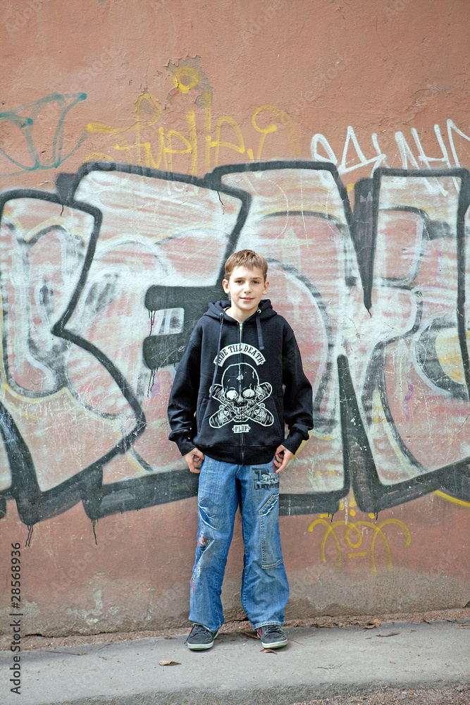 Obraz premium The teenager costs against a wall from graffiti.