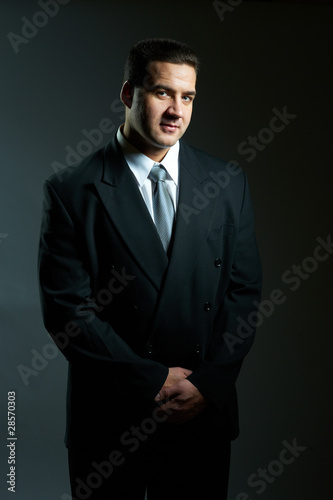 Dark portrait of handsome stylish young man in black suit