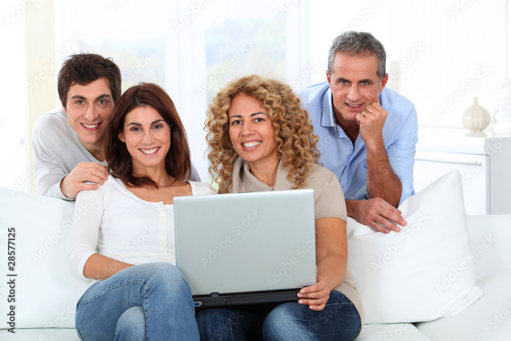 Group of friends sitting in sofa with laptop computer