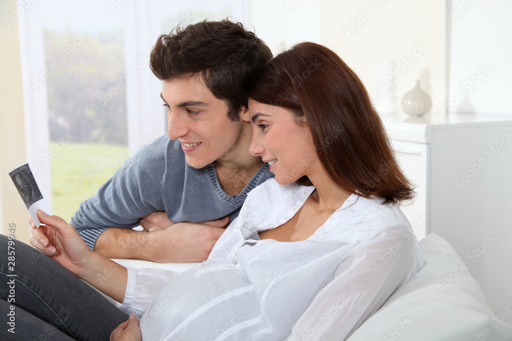 Obraz premium Young couple looking at sonogram of their future baby