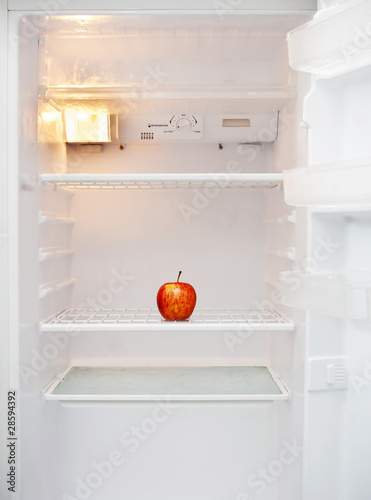 Empty open fridge with only one red apple on the shelf