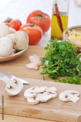 table with raw food ingredients and slieces of white mushrooms