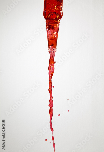 Red liquid pouring out of a glass bottle