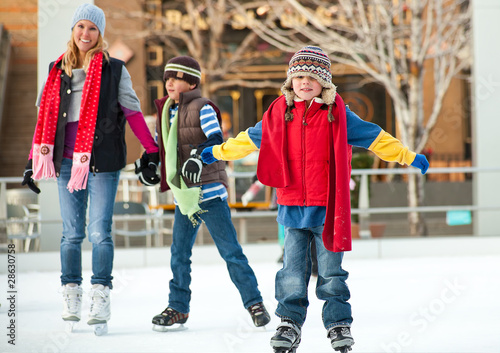 a family skates together at an ice rink
