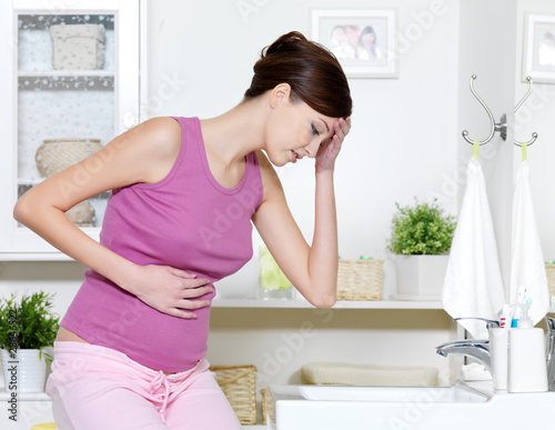 Pregnant woman with strong pain of stomach and nausea photo