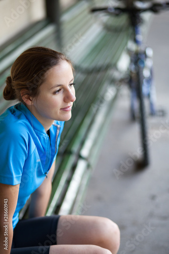 portrait of a pretty female biker outdoors resting on a bench (s