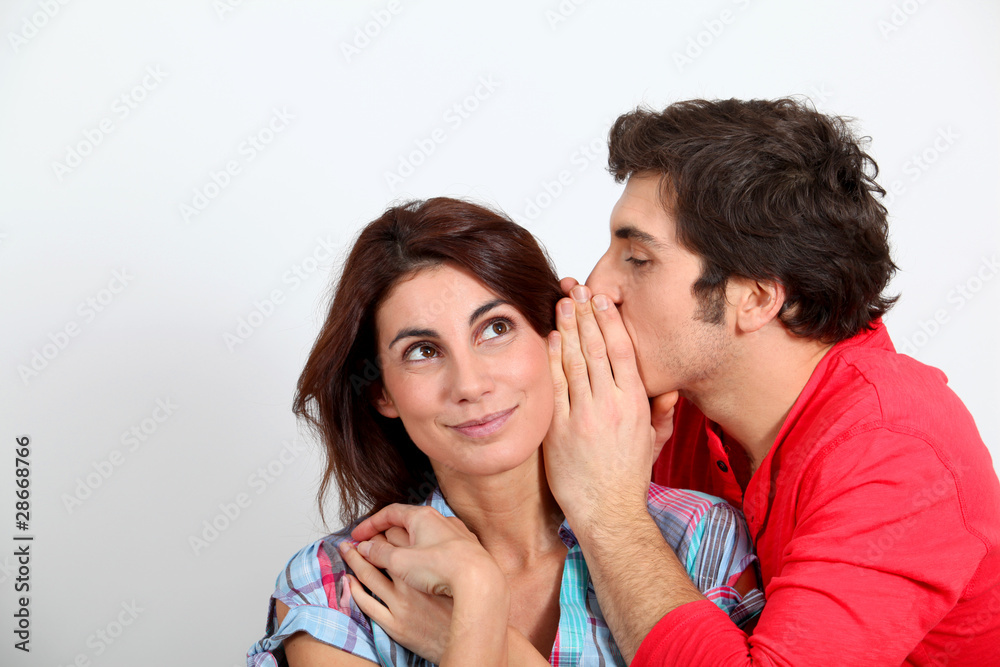 Young man whispering in his girlfriend's ear Young man whispering in his girlfriend's ear