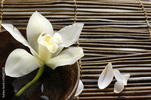 bowl of orchid, petal on bamboo mat