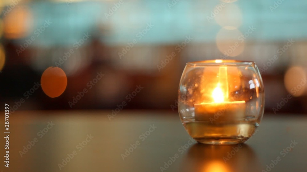 Candle lit inside glass which stands on table in some bar Candle lit inside glass which stands on table in some bar