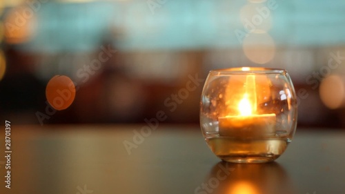 Candle lit inside glass which stands on table in some bar photo