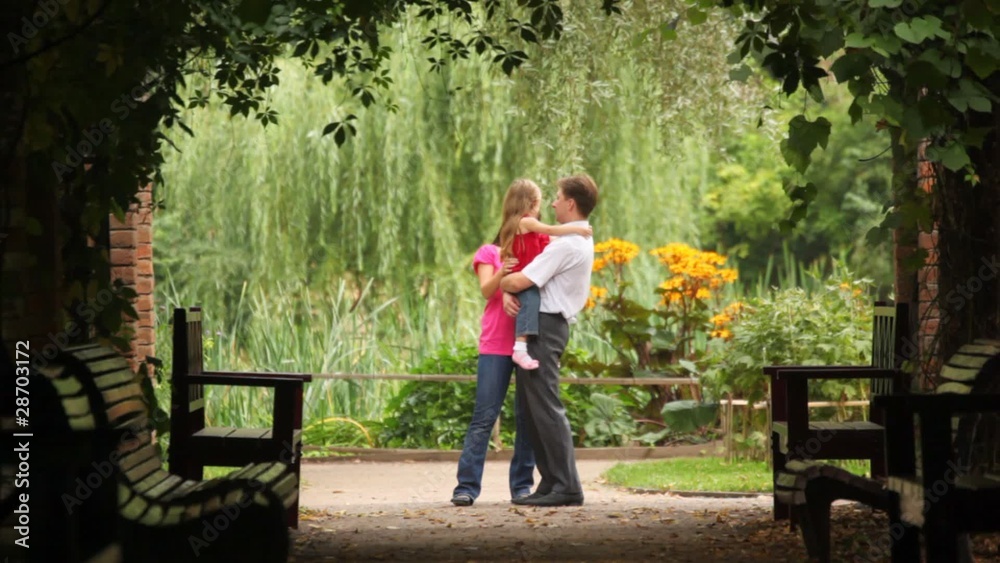 Family carrying one kid hugging embracing and kissing her Family carrying one kid hugging embracing and kissing her
