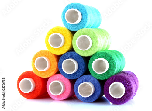 Pyramid of many-coloured bobbins of thread isolated on white