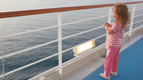 little girl stands on deck of cruise ship photo