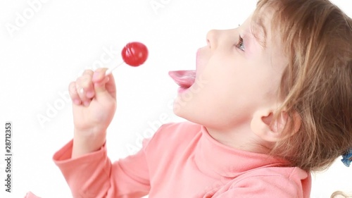 little girl eating lollipop, then looks at camera