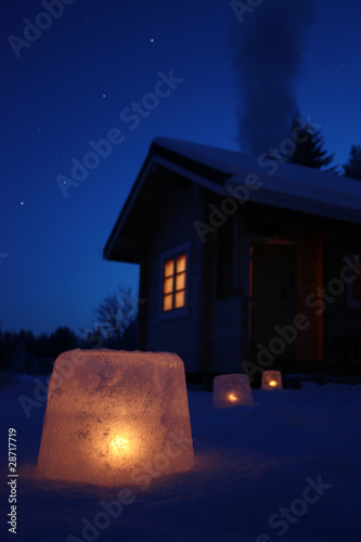 Log cabin in winter night with ice lantern decoration