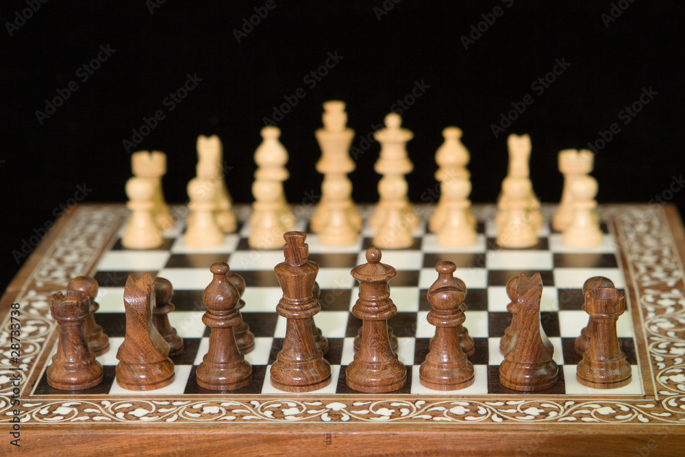 closeup of chess pieces on a wooden chess board closeup of chess pieces on a wooden chess board