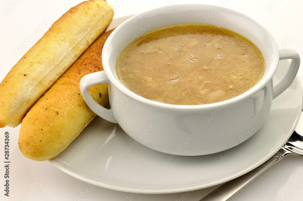 French Onion Soup in a white bowl with bread sticks French Onion Soup in a white bowl with bread sticks