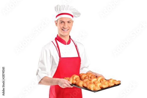 A baker with red apron holding croissants