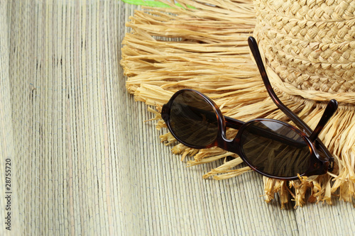 lunettes de soleil et chapeau de paille sur tapis de plage