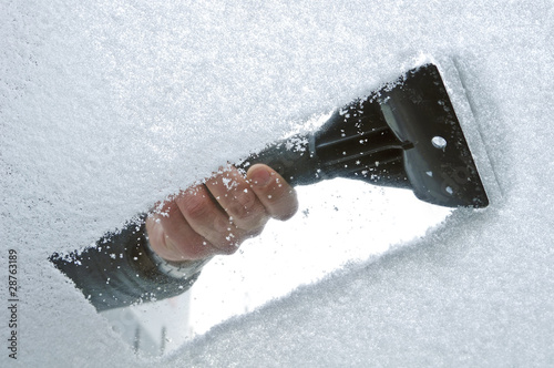 scraping snow and ice from the car windscreen