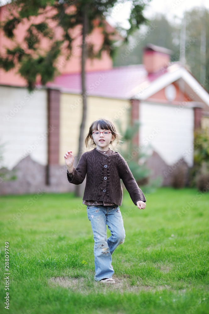 Adorable little girl plays with yellow leaves near the house Adorable little girl plays with yellow leaves near the house