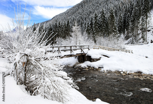 Snow covered bridge across mountain torrent Bióis near Falcade photo