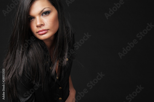Brunette with long hair posing on black background.