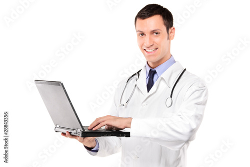 Smiling doctor with stethoscope working on a laptop