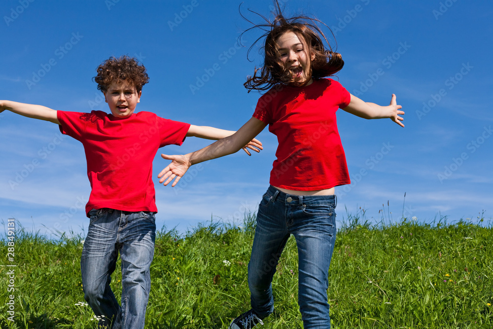 Girl and boy jumping, running against blue sky Girl and boy jumping, running against blue sky