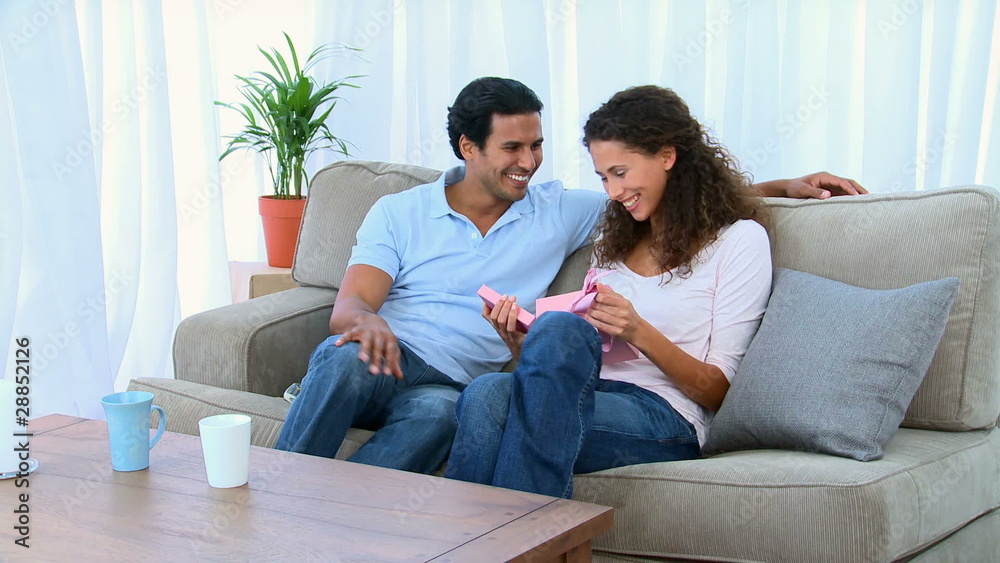 Happy woman opening a gift that was offered by her husband Happy woman opening a gift that was offered by her husband