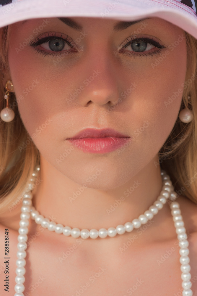 The quiet beautiful woman in a hat and a beads